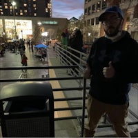 a man standing next to a trash can at night