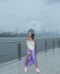 a woman holding an umbrella in front of a city skyline