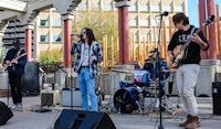 a group of people playing music on a stage in front of a building