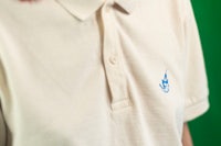 a woman wearing a white polo shirt with a blue logo on it