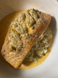 a white plate with a piece of fish and rice