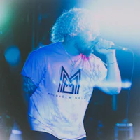 a man with curly hair singing into a microphone