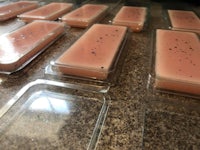 a group of pink soaps in plastic containers on a counter
