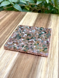 a green and brown stone coaster on a wooden table