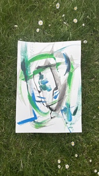 an abstract painting on a piece of paper in the grass