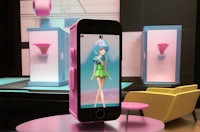 a phone with a doll on it sitting on top of a table