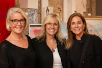 three women posing for a photo in an art gallery