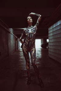 a woman in a bodysuit posing in a parking garage