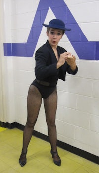 a woman in a black suit and hat is posing for a picture