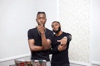 two men standing next to each other in front of a laptop