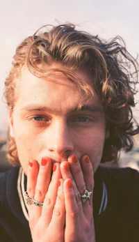 a young man covering his mouth with his hands