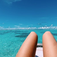 a woman's legs resting on a boat in the ocean