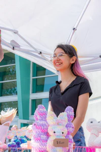 a woman is selling stuffed animals at an outdoor market