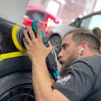 a man with a beard is polishing a car
