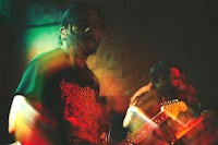 two men playing guitar in a dark room
