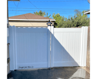 a white fence with a man standing next to it