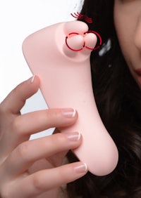 a woman holding up a pink foot massager to her face