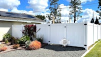 a white fence with solar panels and plants