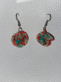 a pair of colorful flower earrings on a white surface