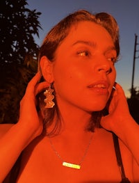 a woman wearing a necklace and earrings at sunset