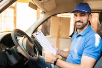 a man sitting in the driver's seat of a car holding a clipboard