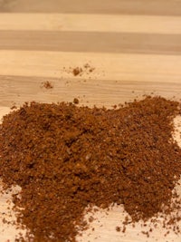 a pile of brown spice on top of a wooden cutting board