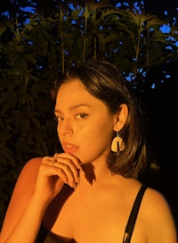 a woman wearing a black top and a pair of earrings