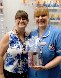 two nurses standing next to each other holding a gift