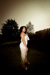 a woman in a white dress standing in a field