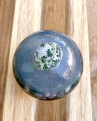 a blue and green glass ball on a wooden surface
