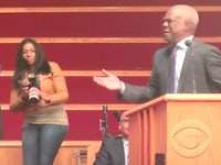 a man in a suit standing at a podium with a microphone