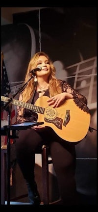 image may contain person, playing a musical instrument, on stage and guitar