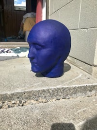 a blue head is sitting on the steps of a building