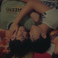 two young men laying on a bed together