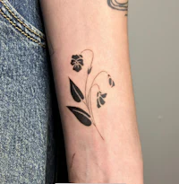 a woman's wrist with a black flower tattoo