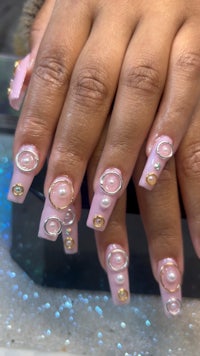 a woman's pink nails with pearls on them