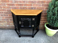 a black corner cabinet with a potted plant next to it