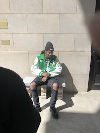 a man sitting on a bench in front of a building