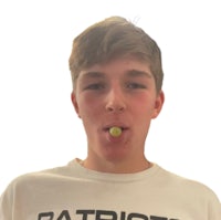a young man is holding a tennis ball in his mouth