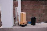 a black and white toilet brush is sitting on a ledge next to a brick wall