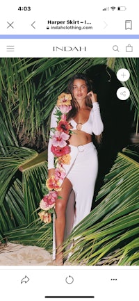 a woman is posing in front of a palm tree