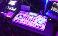 a dj set up in a room with purple lights