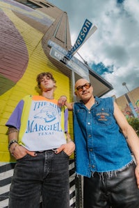 two men posing in front of a mural