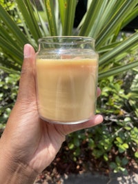 a person holding a candle in front of a palm tree
