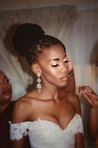 a woman is getting her makeup done for her wedding