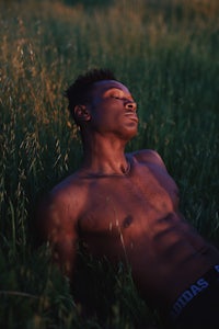 a man laying in a field with his shirt off