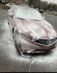 a red acura is being washed in a parking lot