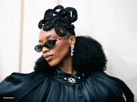 a black woman wearing a black coat and sunglasses