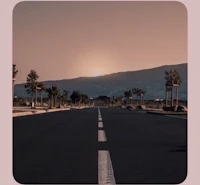 an empty road with the sun setting behind it