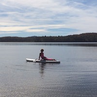 a woman sitting on a paddle board in a lake